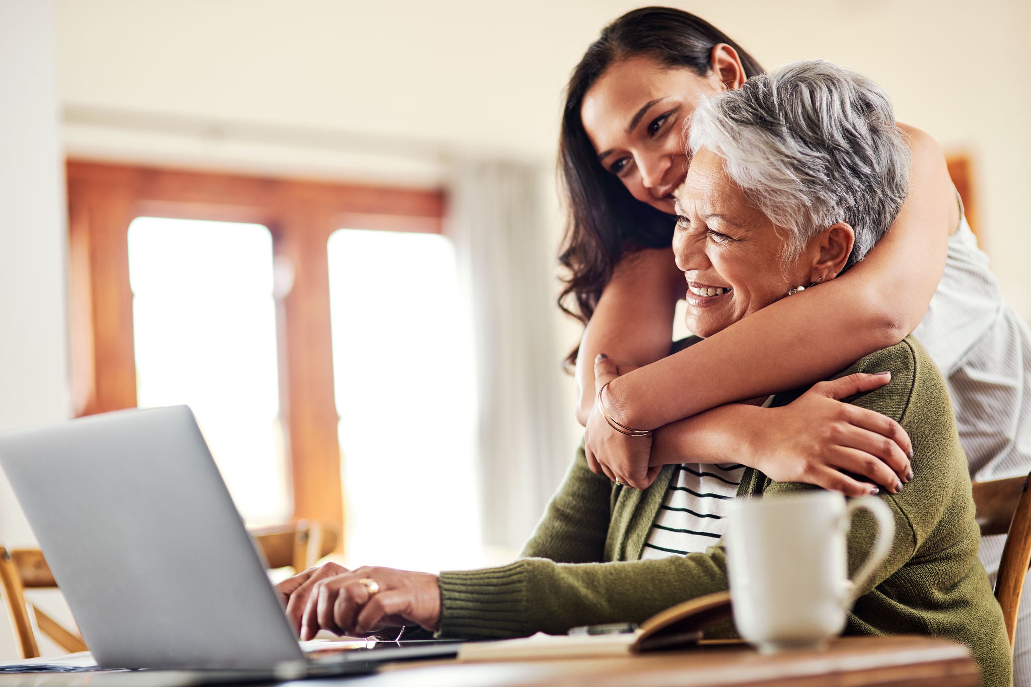 Cropped shot of an attractive young woman hugging her grandmother before helping her with her finances on a laptop